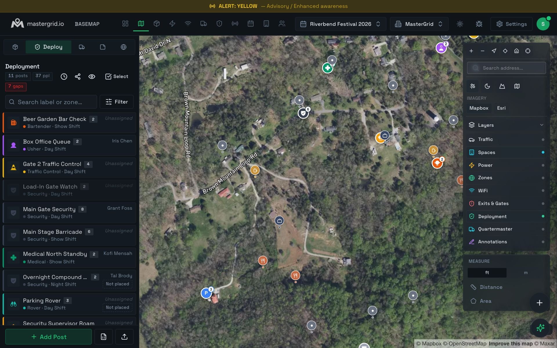 The Basemap Deploy tab: security, medical, usher and traffic posts listed with their shift and who is filling them, the gaps flagged with a count, two posts marked Not placed, and the placed posts as numbered dots over the satellite image of the site.