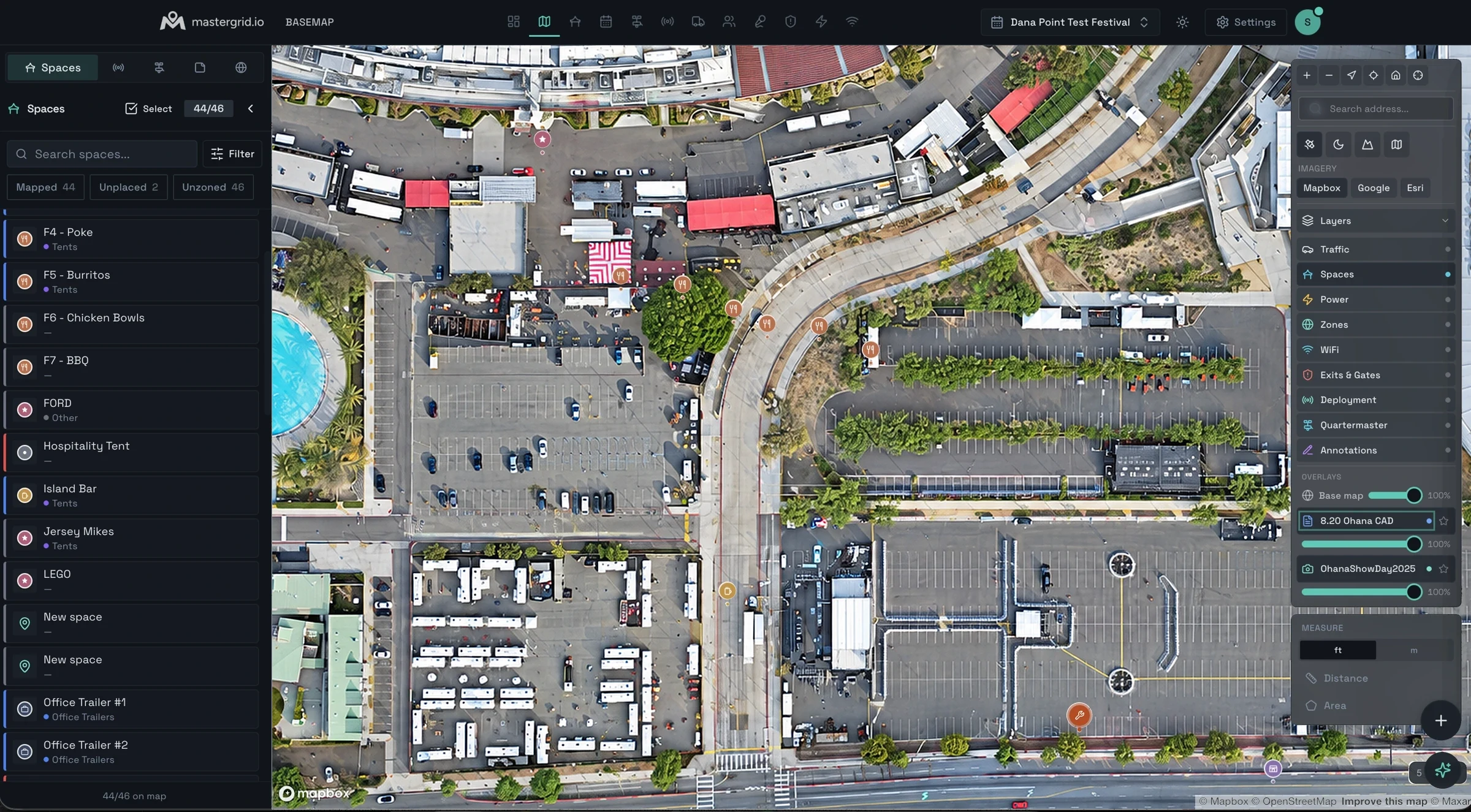 The MasterGrid Basemap over drone imagery of a stadium compound on a build day: the Spaces list on the left, space pins placed on the site, and the Layers panel with its imagery and overlay controls.